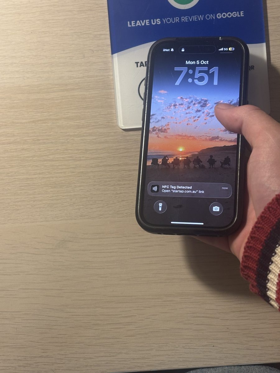 Customer tapping their phone on a Startap review card to leave a Google review